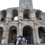 Anfiteatro romano de Arles, com turistas na entrada e os arcos de pedra do século I